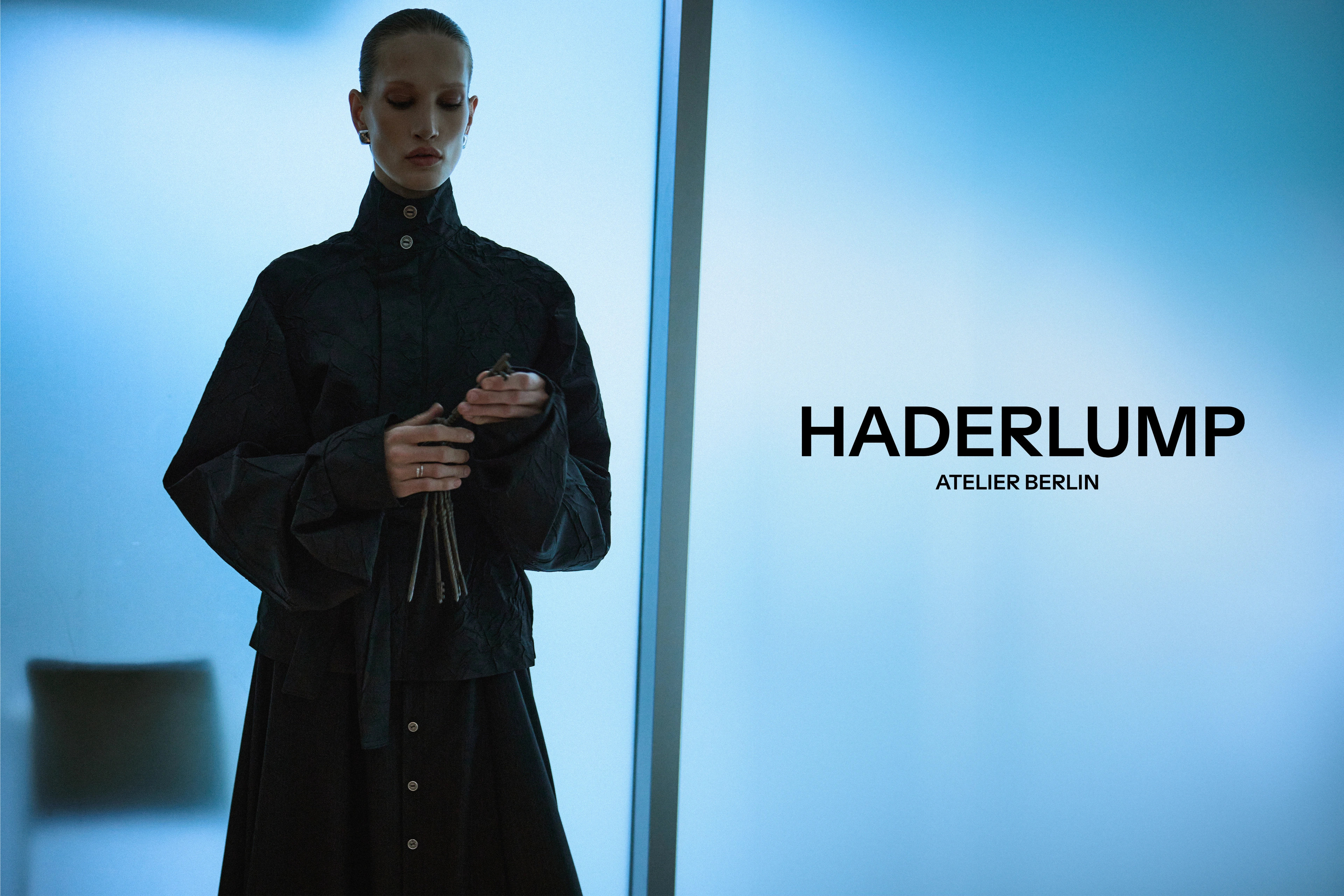 Haderlump Atelier Berlin campaign: models in tailored black and grey outerwear behind frosted glass — 6 / 6