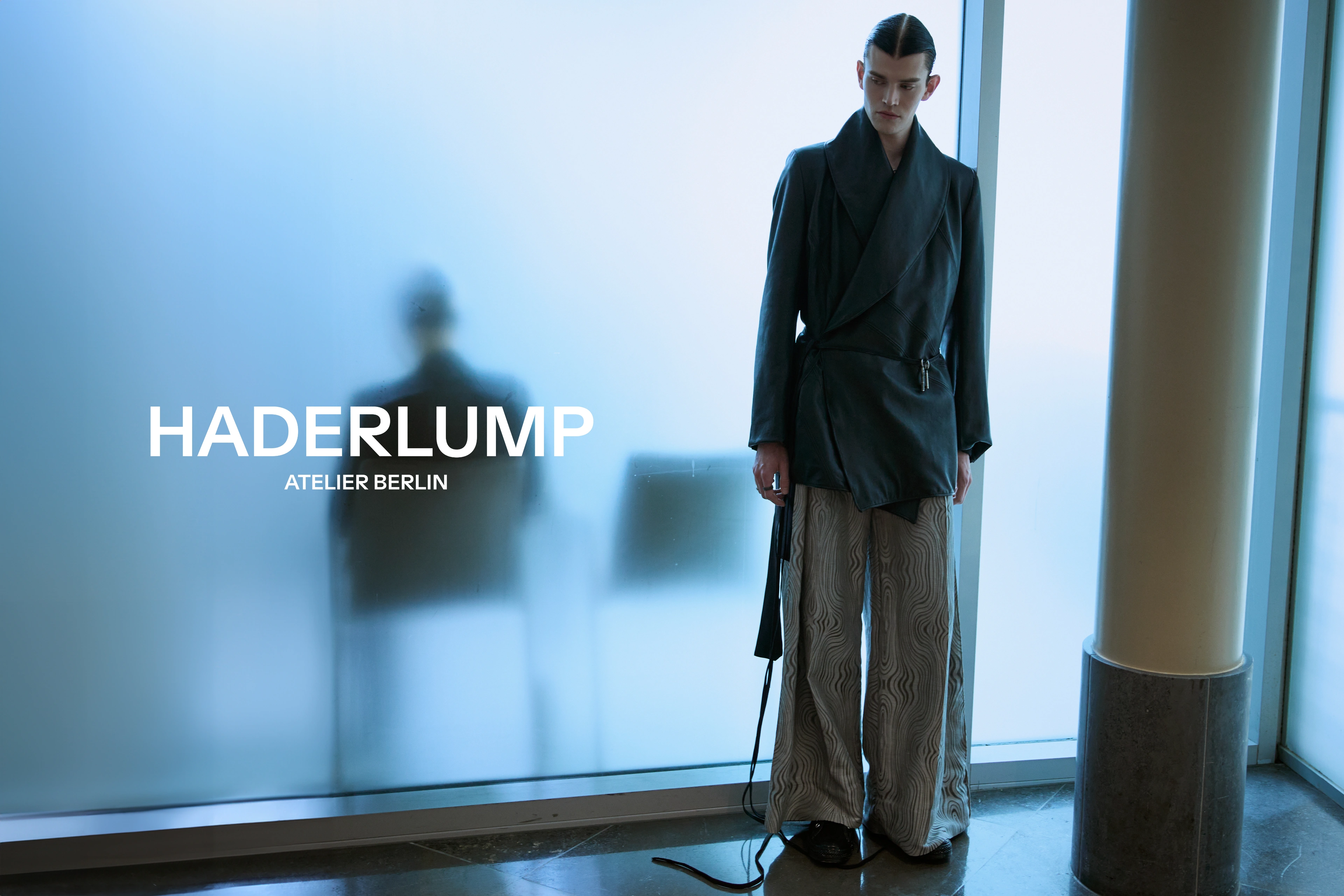Haderlump Atelier Berlin campaign: models in tailored black and grey outerwear behind frosted glass — 2 / 6