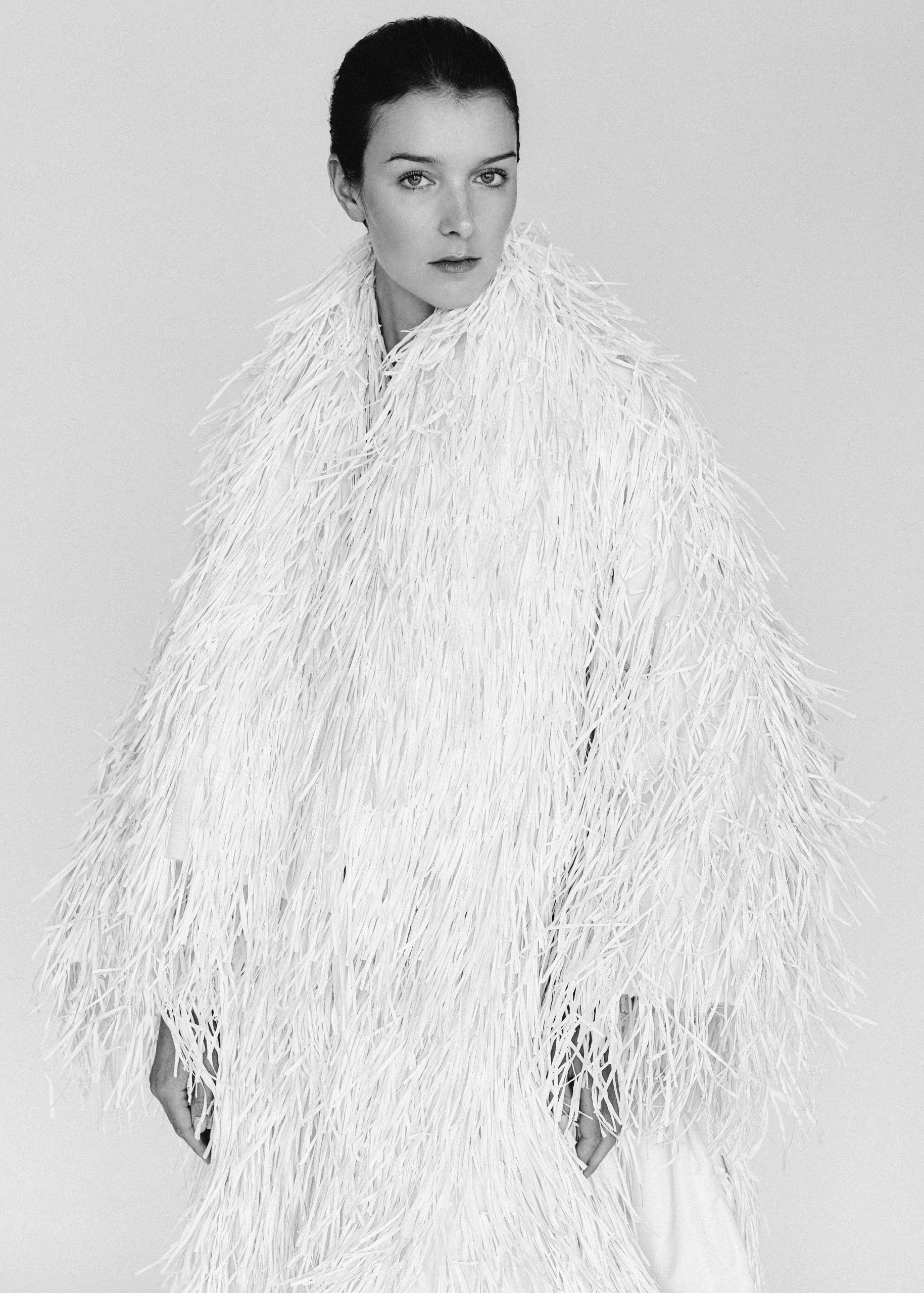 Black and white fashion portrait of a model in a white feathered coat