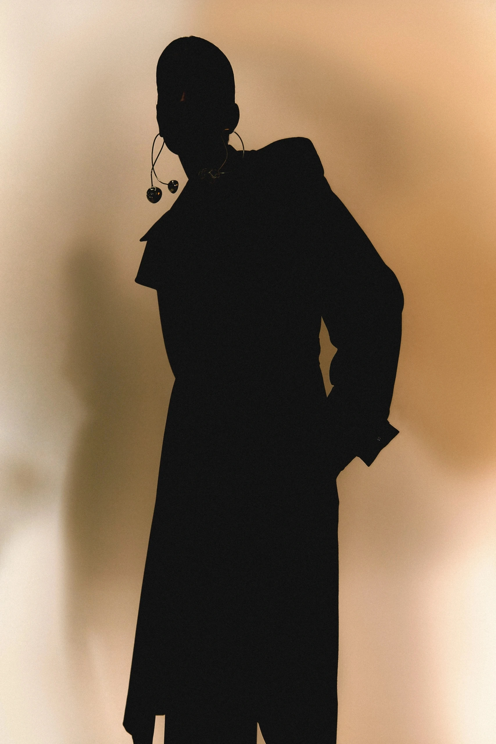 Fashion editorial: black sculptural coat in silhouette, a beauty portrait in a black ruffled collar and a flowing peach slip dress